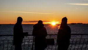 passagiers op het dek van het ms maud expeditieschip bij zonsondergang
