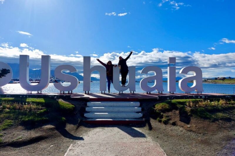 Anina en Virginie bij het bord met de naam Ushuaia in Argentinië