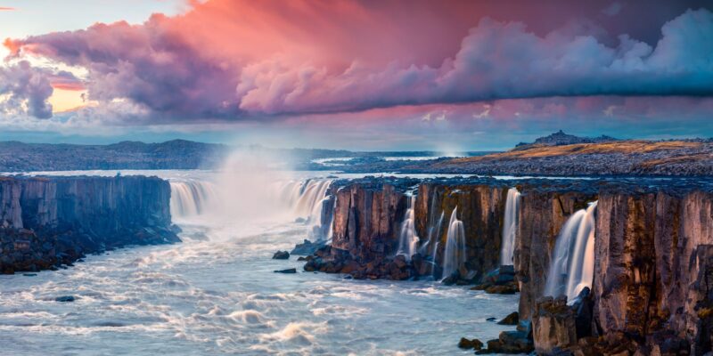 Een waterval in IJsland bij roze gekleurde lucht.